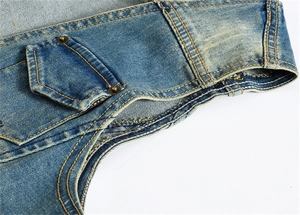 Gros plan sur un gilet en jean bleu vintage avec délavage et poche à rivets métalliques