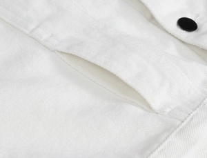 Close-up of a white denim vest showing pocket stitching and a matte black button