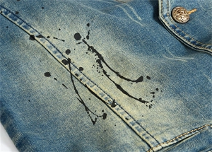Détail du denim délavé bleu avec imprimé éclaboussures d'encre noire et bouton métal
