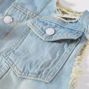 Close-up of light blue denim vest featuring frayed edges and vintage metal buttons