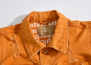 Gros plan détaillé du gilet en jean orange avec étiquette et texture délavée usée