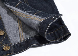 Detailed close-up of dark blue denim hem with engraved metal fashion buttons