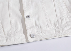 Detail aus hochwertigem weißem Baumwoll-Denim mit geprägtem silbernem Metallknopf