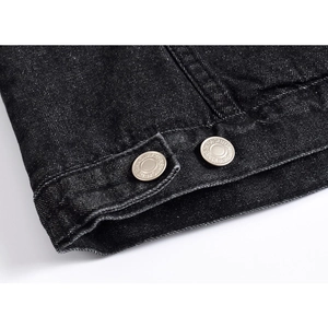 Close-up of black denim fabric texture and silver metal buttons on winter jacket sleeve