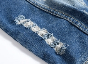 Macro shot of blue denim vest featuring distressed details and white exposed weft threads