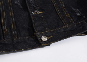 Close-up of black denim vest hem with orange stitching and embossed metal button