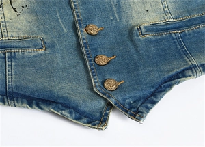 Détail d'un gilet en jean bleu avec boutons métalliques gravés et tissu effet usé