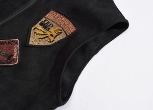 Detailed close-up of heavy embroidery patches on black faux suede vest material