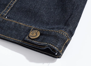 Detail of dark blue denim vest featuring orange stitching and a vintage bronze button