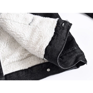 Detailed macro view of black denim jacket with thick white sherpa fleece lining and metal button