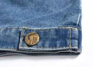 Close-up of light blue denim vest showing twill texture, yellow stitching and metal button