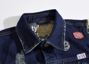 Macro detail of dark blue denim vest collar with vintage patches and logo labels