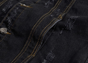 Macro view of black distressed denim vest with yellow contrast stitching and metal button