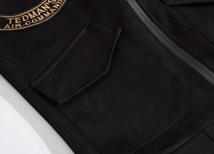 Detailed close-up of tactical black suede vest featuring gold embroidered chest patch