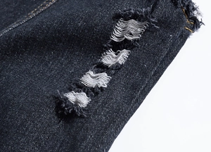 Detailed macro shot of distressed denim fabric with ripped holes and frayed edges