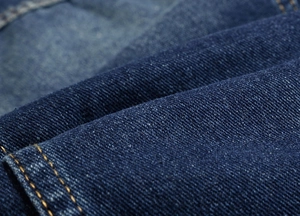 Macro shot of durable blue denim fabric with reinforced yellow stitching on men's vest