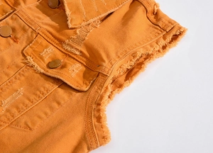 Gros plan détaillé d'un gilet en jean orange avec bords effilochés et boutons métalliques