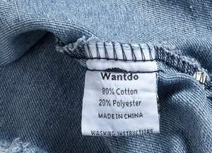 Detailed fabric label showing 80% cotton and 20% polyester blend on blue denim vest