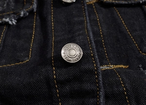 Close-up of black denim fabric with yellow contrast stitching and metal button detail