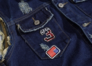 Detailed macro view of denim vest featuring star patch and distressed torn fabric