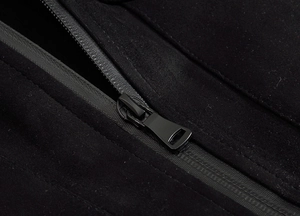 Close-up of a high-quality smooth metal zipper on a black textured fabric vest garment