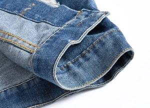 Close-up of contrast orange stitching and washed denim texture on navy vest cuff