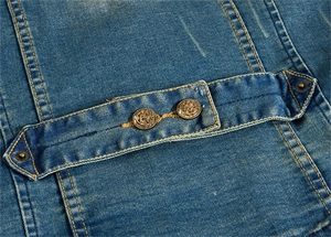Détail de la sangle de réglage dorsale du gilet en jean bleu avec boutons en cuivre