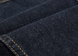Detailed macro view of black denim fabric with contrasting orange double stitching
