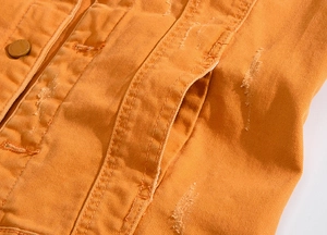 Détail du gilet en jean orange avec déchirures usées et boutons gravés mode fashion