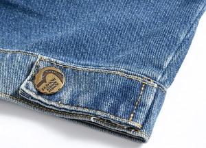 Detailed close-up of blue denim vest fabric with a vintage fashion metal button