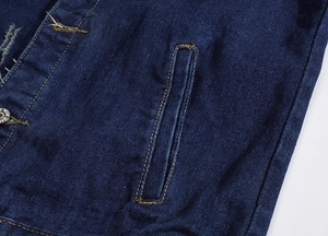 Detailed macro view of dark blue denim vest with reinforced side pocket and worn edges