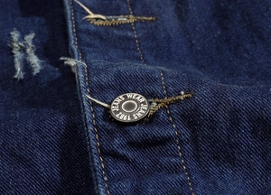 Macro detail of metal buttons and yellow stitching on dark blue denim vest fabric