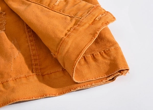 Vue macro du tissu denim orange avec des détails déchirés usés et des coutures renforcées
