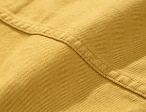 Macro view of yellow twill denim fabric with durable reinforced double stitching