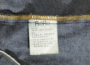 Detailed laundry care label showing 98% cotton and 2% spandex fabric composition on denim vest