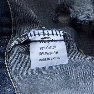 Detail of dark blue denim vest fabric label showing 80% cotton and 20% polyester material