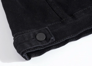 Close-up of black twill denim fabric texture with matte metal button and jeans engraving