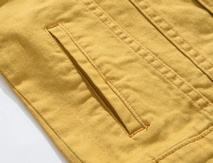 Detailed close-up showing double-needle stitching and side pocket on yellow denim jacket