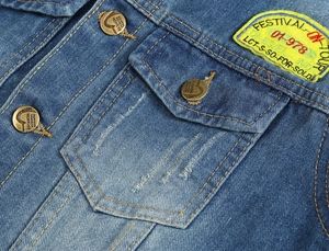 Dettaglio del gilet in denim blu slavato con toppa ricamata e bottoni in metallo