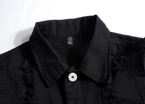 Détail du gilet en jean noir montrant des déchirures aux épaules et des boutons étoilés