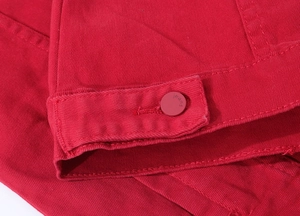 Macro shot of red denim fabric texture and round metal button with jeans engraving