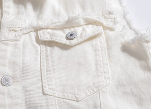 Detail der weißen Denim-Weste mit Fransenrand, Pattentasche und gravierten Metallknöpfen