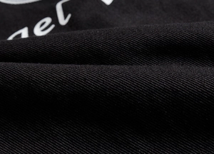 Detailed macro view of black heavy cotton twill fabric with white embroidered text detail