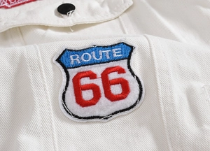 Close-up of Route 66 embroidery patch and metal button on white denim vest