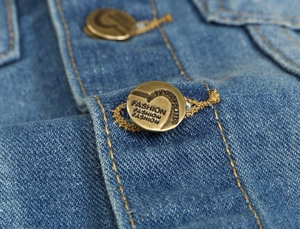 Dettaglio macro di bottoni in ottone con incisione fashion su tessuto gilet denim