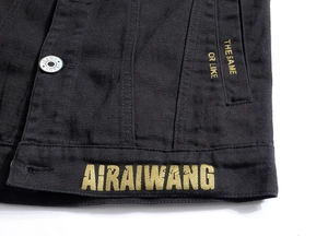 Détail du gilet en jean noir montrant l'imprimé jaune AIRAIWANG et la broderie fine