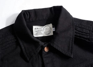 Close-up of black denim vest collar with metal button and stitched shoulder details