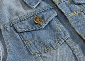 Detail of light blue denim vest with yellow contrast stitching and fashion metal button