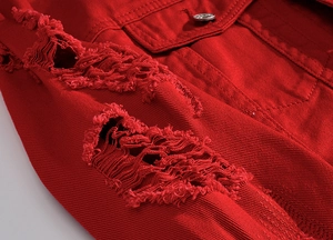 Dettaglio della giacca in denim rosso con strappi usurati e bottone in metallo argento