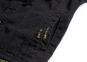 Vue détaillée d'un gilet en jean noir avec broderie jaune et détails de tissu usé